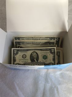 three stacks of one hundred dollar bills in a white box