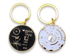 two keychains with different designs on them, one is gold and the other is white