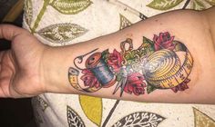 a woman's arm with a tattoo on it that has flowers and scissors in it