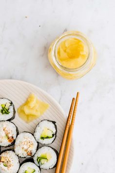 sushi on a plate with chopsticks next to it and a jar of honey