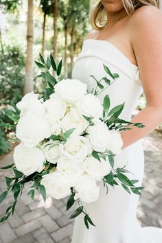 a woman holding a bouquet of white flowers