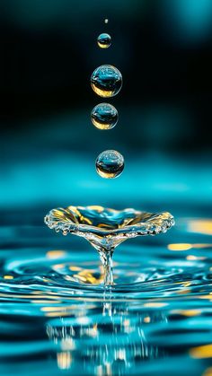 three drops of water are falling into the blue and yellow water that is splashing