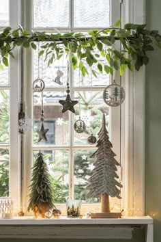 a window sill with christmas decorations hanging from it's sides and trees on the windowsill