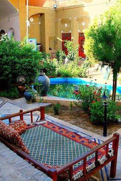 an outdoor area with a pool, patio furniture and potted trees in the background