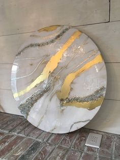 a white and gold plate sitting on top of a brick floor next to a wall