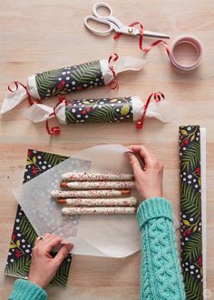 a person is decorating christmas cookies with icing and sprinkles on a table