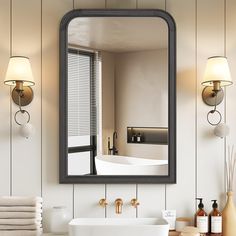 a bathroom sink sitting under a large mirror next to a bathtub and two lamps