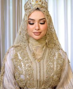 a woman wearing a gold and white wedding dress with a veil on top of her head