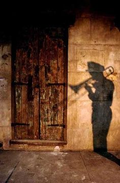 a shadow of a man with a hat on his head standing in front of a door