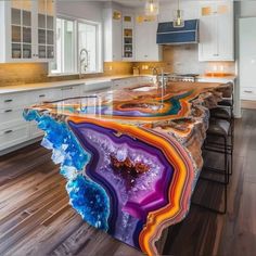 a large kitchen island with colorful marble counter tops and wooden flooring in the middle