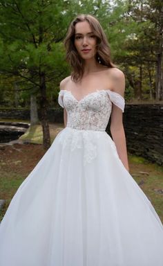 a woman in a white wedding dress posing for the camera with her hands on her hips