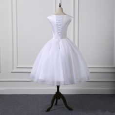 a short white dress on a mannequin stand in front of a white wall