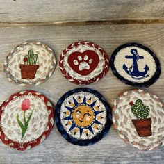 four coasters with different designs on them sitting on top of a wooden table next to a potted plant