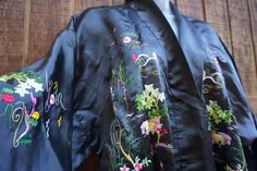 "Vintage charcoal/black floral embroidered robe. Open front.  No waist tie. Good vintage condition! condition - see photos ✂Measurements✂ shoulders: 24\" length: 54\"" Black Fitted Long Kimono, Fitted Long Black Kimono, Vintage Black Kimono For Spring, Black Embroidered Long Sleeve Kimono, Black Kimono With Floral Embroidery, Fitted Black Traditional Kimono, Black Floral Embroidered Kimono, Fitted Traditional Black Kimono, Traditional Fitted Black Kimono