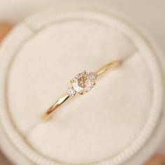 a diamond ring sitting on top of a white box with gold trim around the band