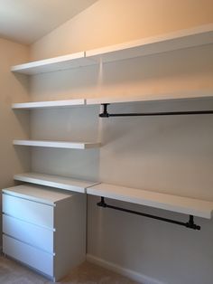 an empty room with white shelves and drawers