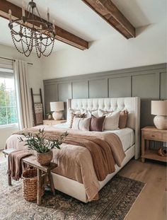 a bedroom with a large bed, chandelier and two tables in front of the window