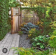 a wooden gate surrounded by greenery and flowers in a garden with stone walkway leading to the front door