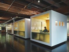 a person sitting at a desk in a room with glass partitions on the walls