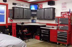 a garage with lots of work tools and cabinets on the walls, along with a bed