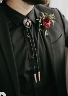 a man wearing a black suit with a red flower on it's lapel