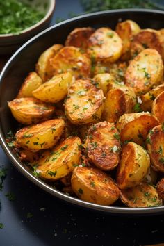 a pan filled with cooked potatoes on top of a table next to some parsley