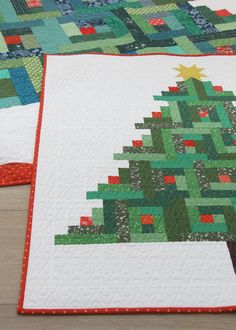 two quilted christmas trees sitting next to each other on top of a wooden table