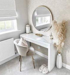 a white desk with a mirror, chair and vase on it in front of a window