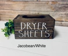 a wooden box with the words dryer sheets written on it next to a plant