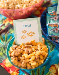 fish snacks are displayed in bowls on a colorful tablecloth with place cards for the guests to eat