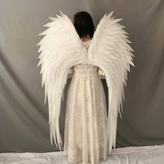 the back of a woman's dress with large white angel wings on her shoulders