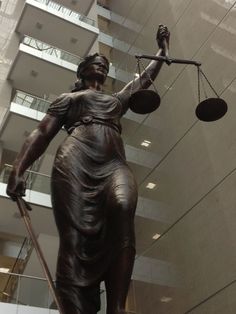 a statue of lady justice holding two scales in front of a tall building with balconies