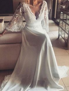 a woman sitting on top of a couch wearing a white dress with long sleeves and lace