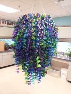 a very colorful chandelier hanging from a ceiling in an office building or school