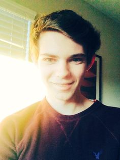 a young man is smiling in front of a window with the sun shining through it