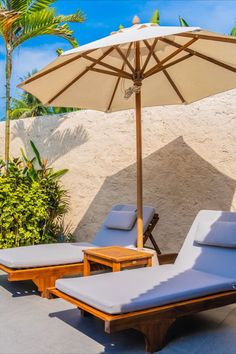 two chaise lounge chairs under an umbrella