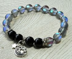 Moon And Stars Gemstone Bracelet, Matte Blue Aura Quartz Mystic Bracelet, Black Tourmaline Healing Bracelet, by RainTreeEssentials on Etsy https://www.etsy.com/listing/731398110/moon-and-stars-gemstone-bracelet-matte Silver Bracelets With Moon Charm And Round Beads, Silver Bracelet With Moon Charm And Round Beads, Black Moonstone Spiritual Jewelry, Spiritual Black Moonstone Jewelry, Silver Round Beads Crystal Bracelet For Healing, Aura Quartz Bracelet, Blue Aura Quartz, Meteorite Jewelry, Rainbow Aura Quartz