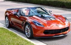 a red sports car is parked on the side of the road in front of some bushes