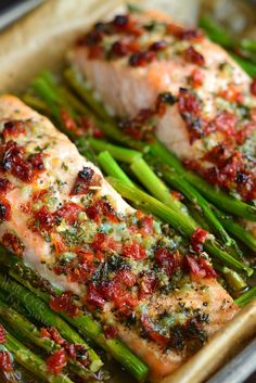 salmon and asparagus on a baking sheet with seasoning sprinkles