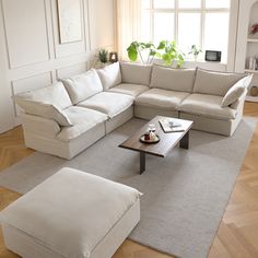 a living room with white couches and pillows on the floor in front of a large window