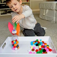 a young boy is playing with toys on the floor in front of a white box