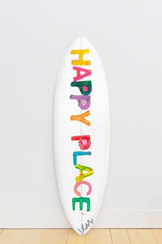 a white surfboard with the words happy birthday written in multicolored crayons