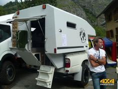 a man standing next to a white truck with a camper on it's back