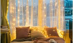 a bedroom with lights on the curtains and a bed in front of a large window