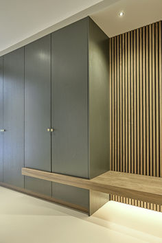 an empty room with wooden walls and shelves on the wall, next to a bench