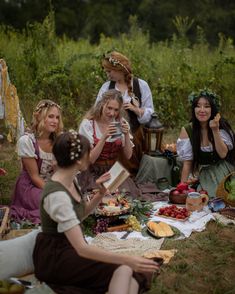 a group of women sitting on top of a grass covered field