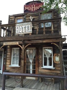 an old wooden building with signs on the front and side windows that read bath house