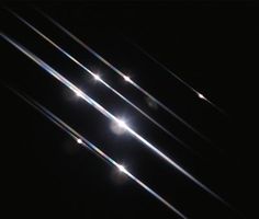 the sun shines brightly in the dark sky above some thin strips of light that appear to be flying through the air