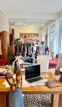 a person's feet resting on a table in front of a laptop computer and clothes