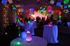 a room filled with lots of tables covered in white tablecloths and colorful balloons